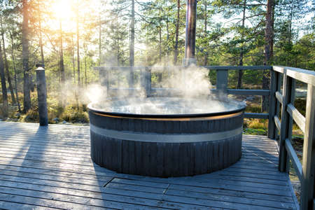 Modern big barrel outdoor hot tub in the middle of forest. The hot tub's soothing warm water relaxes muscles and eases tensions, so your worries can simply melt away.の写真素材