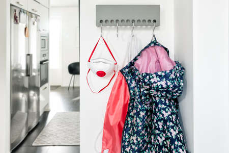 Wall Mounted coat rack in entrance hall with girl's jacket, bag and respirator mask hanging on it.の写真素材