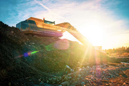 Yellow excavator on a road construction at sunset.の写真素材