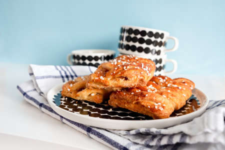 Breakfast setup with Danish pastries and coffee cups, ready to be filled on soft blue background.の写真素材