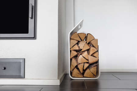 A fireplace with a stand full of chopped logs.の写真素材