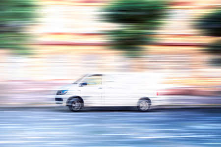 White van speeding down a city street.の写真素材