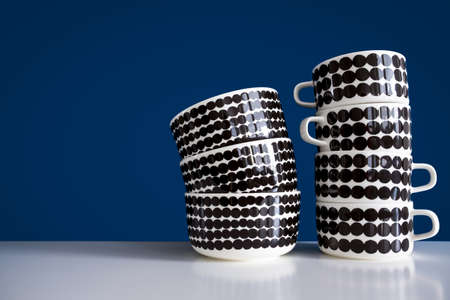 Stack of crockery on white wooden table against blue wall. Bowls and mugs.の写真素材