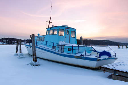 Boat is stuck in ice in the winter, Kaarina, Finland. Beautiful sunset in the background.の写真素材