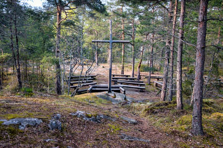 Summer scene of wooden Christian cross in a simple forest church. Wooden benches and altar.の写真素材