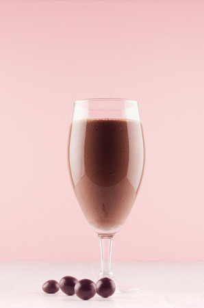 Exquisite light milk chocolate dessert with chocolate balls, whipped cream, red straw on modern elegant pink color background, vertical.の写真素材