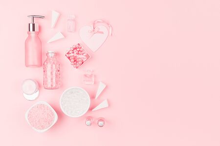 Cosmetic products and accessories in pink color - cream, bath salt, essential oil, soap, towel,  pearls, bottles, heart, bowl on pink background, top view.の写真素材