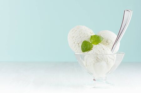 Homemade creamy ice cream scoops in transparent glass ice-cream bowl with green mint, silver spoon...