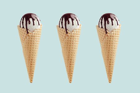 Set of three white ice cream in crisp waffle cones with chocolate sauce on  green background, mock...