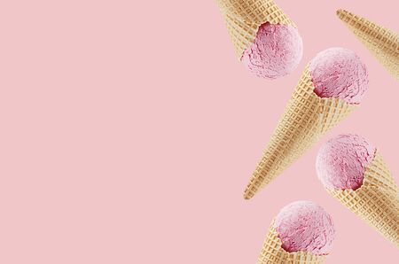 Strawberry ice cream in crisp waffle cones as decorative border on pastel pink background, mock up, copy space.の写真素材