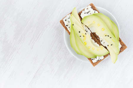 Organic season sandwiches on dry brown grain crispbread with fresh avocado slices, olive oil, black...