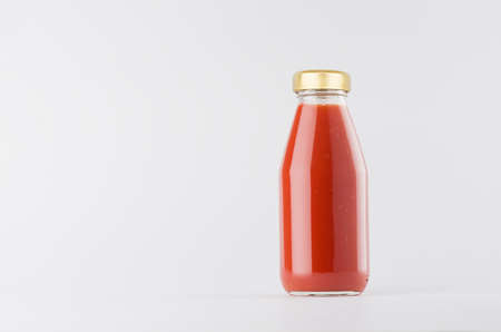 Red tomato juice in glass bottle with gold cap mock up on white background with copy space, template for packaging, advertising, design product, branding.の写真素材