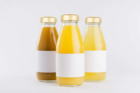 Orange, yellow fruit juices collection in glass bottles with cap, white blank labels, group mock up...