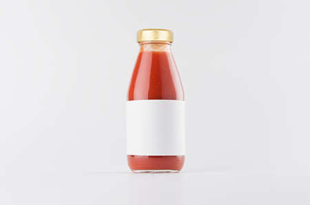 Red tomato juice in glass bottle with gold cap and white blank label mock up on white background with copy space, template for packaging, advertising, design product, branding.の写真素材