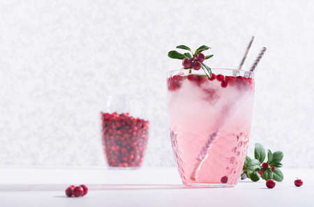 Fresh healthy lemonade with red bilberry, ice, green berry leaves on white wood table, copy space.の写真素材