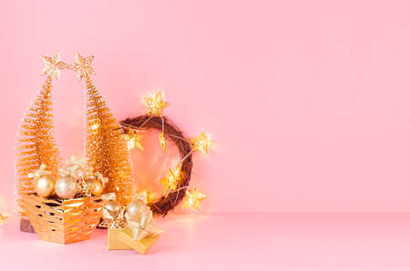 Christmas bright and gentle background with glitter gold decorations, christmas tree, wreath, lights on elegant pastel pink background.の写真素材