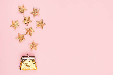 Festive New Year shopping - gold glitter wallet with fall stars on soft light pink background, top view.の写真素材