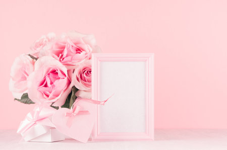 Modern fashion Valentine days background - blank frame, rich roses, trendy pink heart with ribbon, gift box on white wood board, copy space.の写真素材