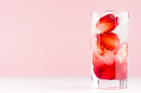 Tropical fresh strawberry cocktail with ice cubes, pieces berry on pastel pink background, copy space.の写真素材