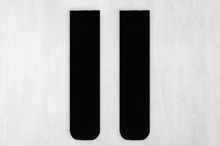 Pair blank black tall socks front view flat lay on white wood board as mock up for design, print, presentation, advertising, top view.の写真素材