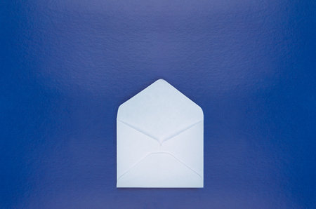 Open blank white envelope on dark blue background, top view, copy space, mockup, horizontal.