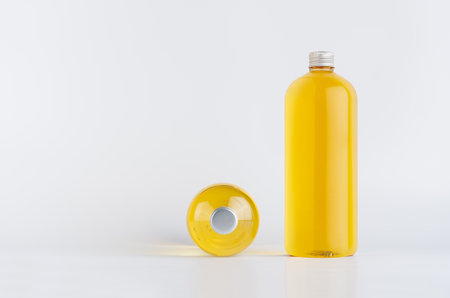 Set of two transparent plastic tall bottles standing and lying with orange liquid, oil or cosmetic produce and silver cap, mockup on white background, front and top view.の写真素材