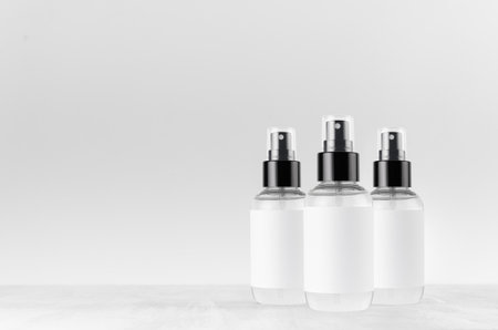 Transparent spray bottles for cosmetics product with white blank label on white wood board, mock up for branding, advertising, presentation, design.の写真素材