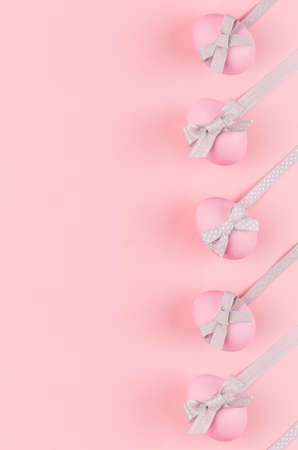 Pink easter eggs with gray bows and ribbons as border on pastel pink background, vertical, story.の写真素材