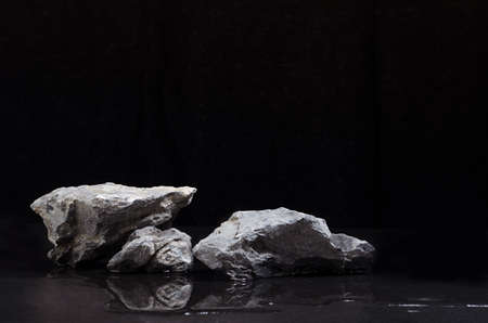 Luxury natural stone podium with water as shore at night for showing packaging and product on black background.