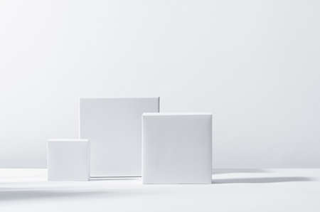 White square podiums in sunlight with shadow on white background. Trend fashion showcase for cosmetic products, goods, shoes, bags, watches.の写真素材