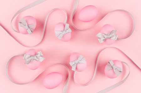 Elegant and girlish easter background - easter eggs with silver bow, wavy ribbons on pastel pink...