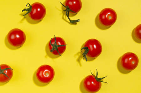 Ripe cherry tomato with shadow on yellow background, top view, food color pattern.の写真素材