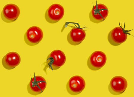 Vegetable colorful seamless pattern - ripe cherry tomato with green tail and shadow on yellow background, top view.の写真素材