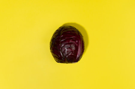 Juicy purple cabbage head with shadow on yellow color with copy space, top view. Modern food background.の写真素材