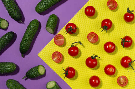 Summer color food background - red cherry tomatoes, green gherkin cucumber in sunlight with shadows on red and violet backdrop, flat lay, vertical.の写真素材
