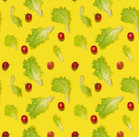 Food colorful vegetables seamless pattern - cherry tomatoes, green salad leaves in hard light with shadow on yellow background, flat lay, square.の写真素材