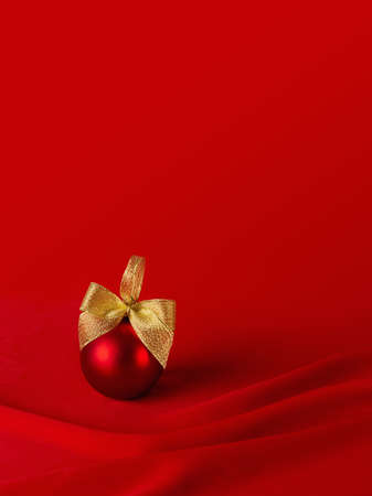 Exquisite glossy ball with golden bow on elegant dark silk backdrop with smooth waves, copy space, vertical. Rich christmas background for design of poster, flyer, card, brochure, story.の写真素材