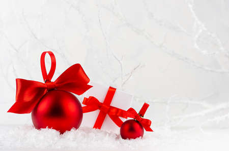 Traditional christmas decoration and present boxes with red ribbons and bows closeup in white snow in elegant soft light fairy winter forest with frosty branches, copy space. New Year background.の写真素材