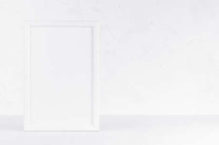Simple modern white wood blank rectangle photo frame on wood board in gentle simplicity soft light interior with plaster wall. Mockup for presentation, portfolio, message, text, design.の写真素材