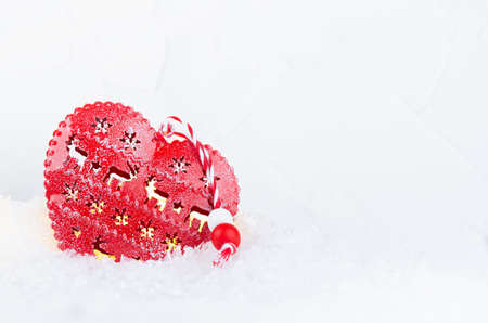 Christmas background with red heart and lights glowing inside in bright shimmer snow closeup, copy space.の写真素材