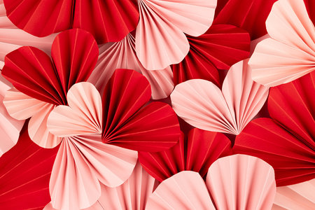 Fun Valentines day festive background in asian style - heap pink and red paper hearts of folded fans on gentle pastel pink color backdrop as hearts texture, top view.の写真素材