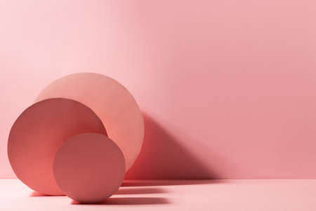 Fashion minimal contrast pink stage in modern style with round boxes standing as abstract composition in sunlight with shadows, copy space. Scene for presentation products, advertising, design.の写真素材
