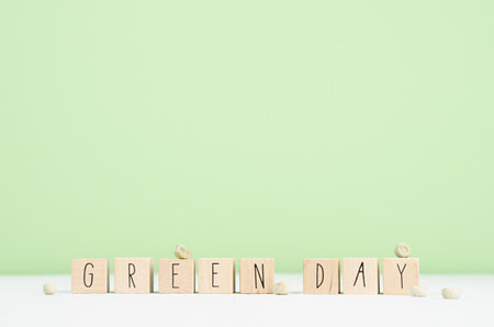 Lettering on wood cubes - Green day and seeds of peas on white wood table and pastel green wall, copy space. gardening background.の写真素材