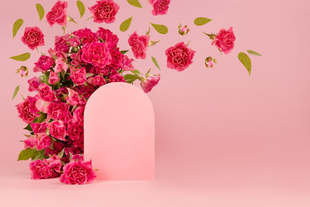 Spring fresh pink roses as arches with empty rounded door as podium mockup with flying green leaves, buds as swirl for presentation cosmetic products, goods, advertising, design on pink background.の写真素材
