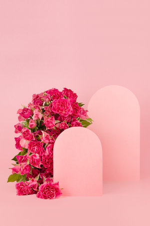 Spring pink flowers roses as rounded arch, two blank rounded spaces as podiums on abstract pink stage mockup for showing of cosmetic products, goods, advertising, design, vertical. floral background.の写真素材