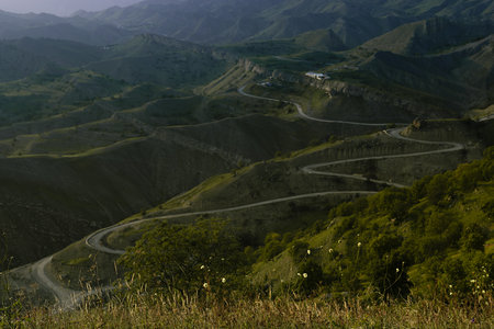 Zen serenity mountain landscape - high lush green mountain ridges , serpentine road and village away...