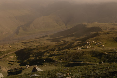 Sunny yellow and green mountain valley with velvety hilly slopes in golden sunlight with shadow, light mist on sunset in summer, detail. Mountain landscape, adventure in Dagestan.の写真素材