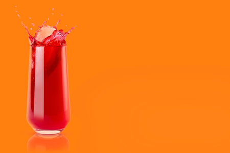 Cherry fresh red juice in glass with reflection, drops and splashind on orange background, copy space. Vitamin organic summer drink with splashes, drops and motion in glass.の写真素材