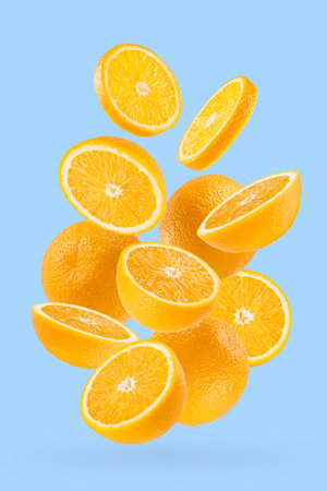 Juicy oranges closeup fly as flow, art composition. Whole, half and round slice of fruits on pastel blue background with shadow. Exotic fruits for advertising, design, label product, poster, card.の写真素材