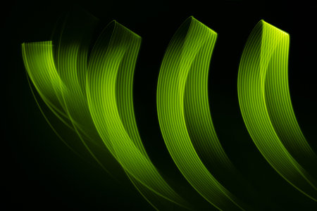 Green glowing neon wave of light as curls or swirl with smooth stripes on black background, pattern. Abstract background with motion light effect in hipster style.の写真素材
